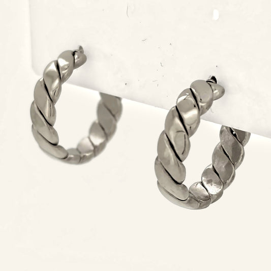 Denoon London chunky twisted hoop earrings, silver-tone, close-up side view on cream