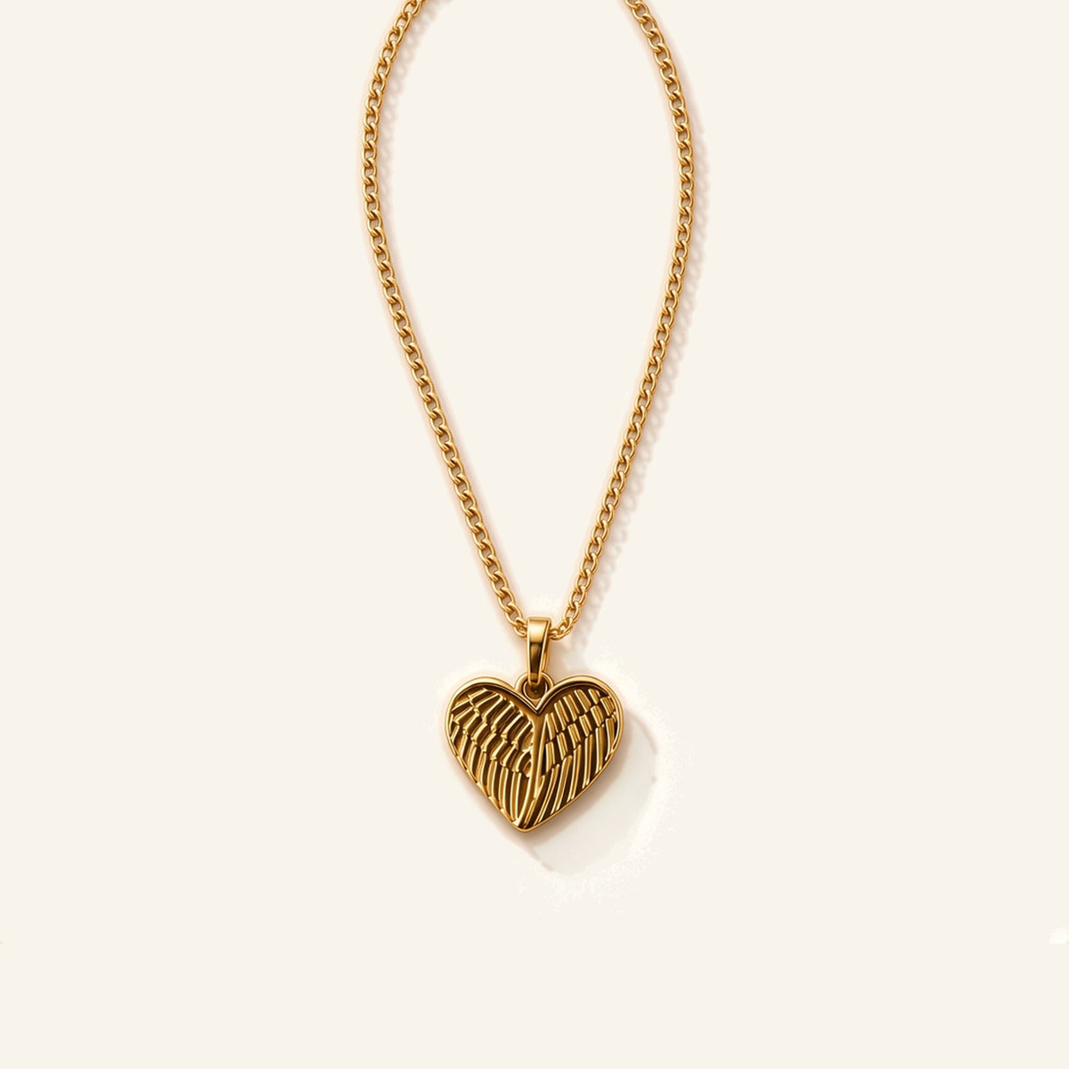 Denoon London Angel Wing Heart necklace in gold-tone stainless steel, 45cm chain, flat lay on cream