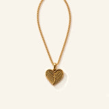 Denoon London Angel Wing Heart necklace in gold-tone stainless steel, 45cm chain, flat lay on cream