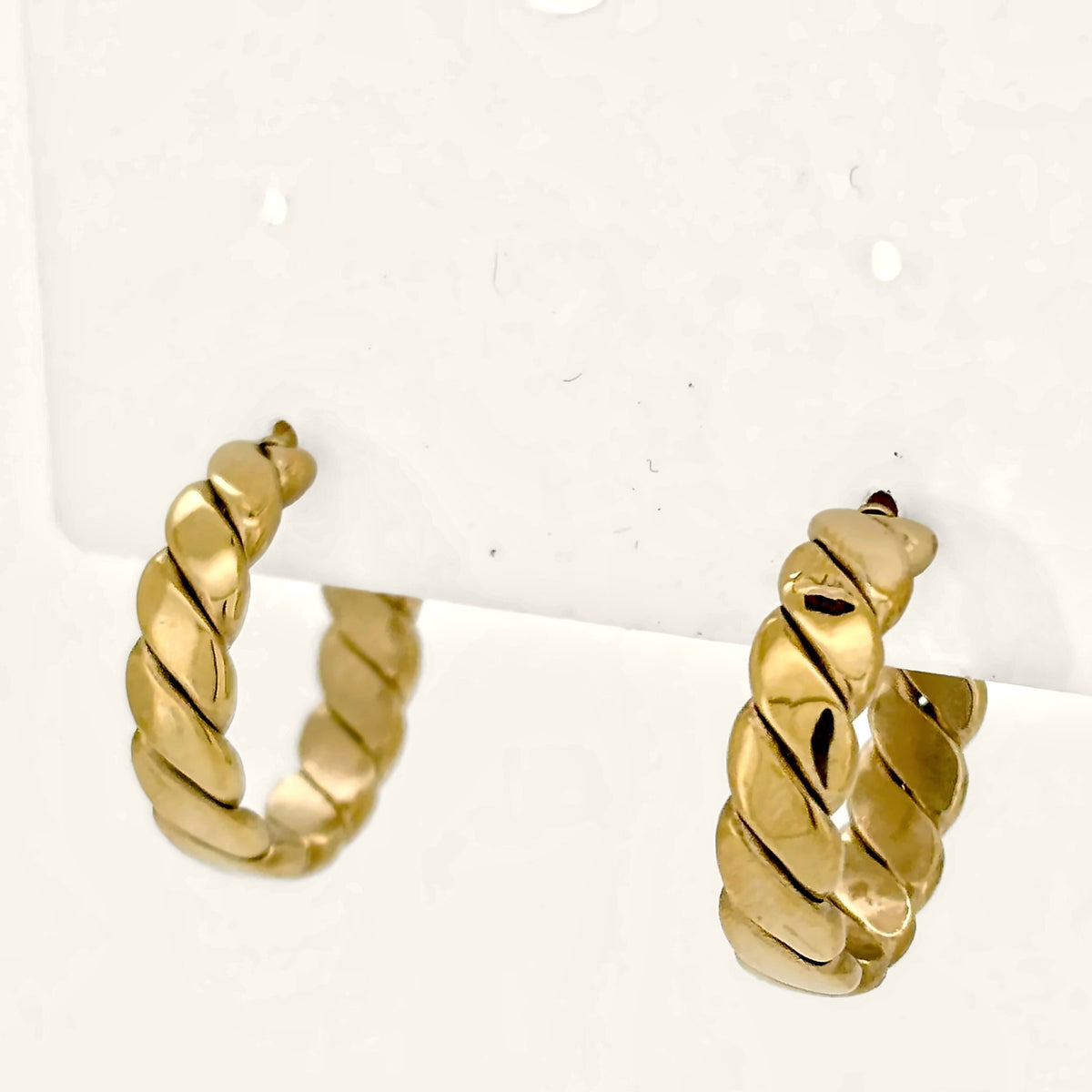 Denoon London chunky twisted hoop earrings, gold-tone, side view on cream