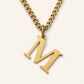 Denoon London Classic Initial necklace close-up, gold-tone letter M, on cream