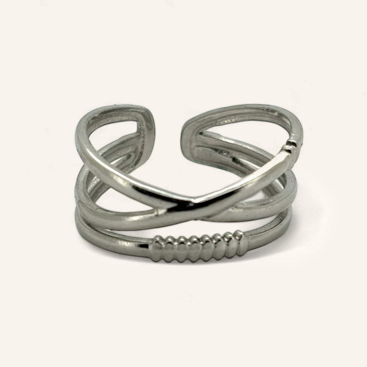 Denoon London crossover statement ring, silver-tone, on a cream background