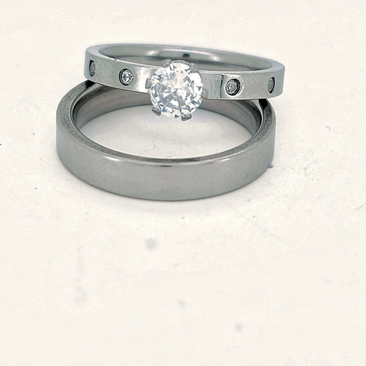 Denoon London engagement ring and wedding band set, silver-tone, on a cream background