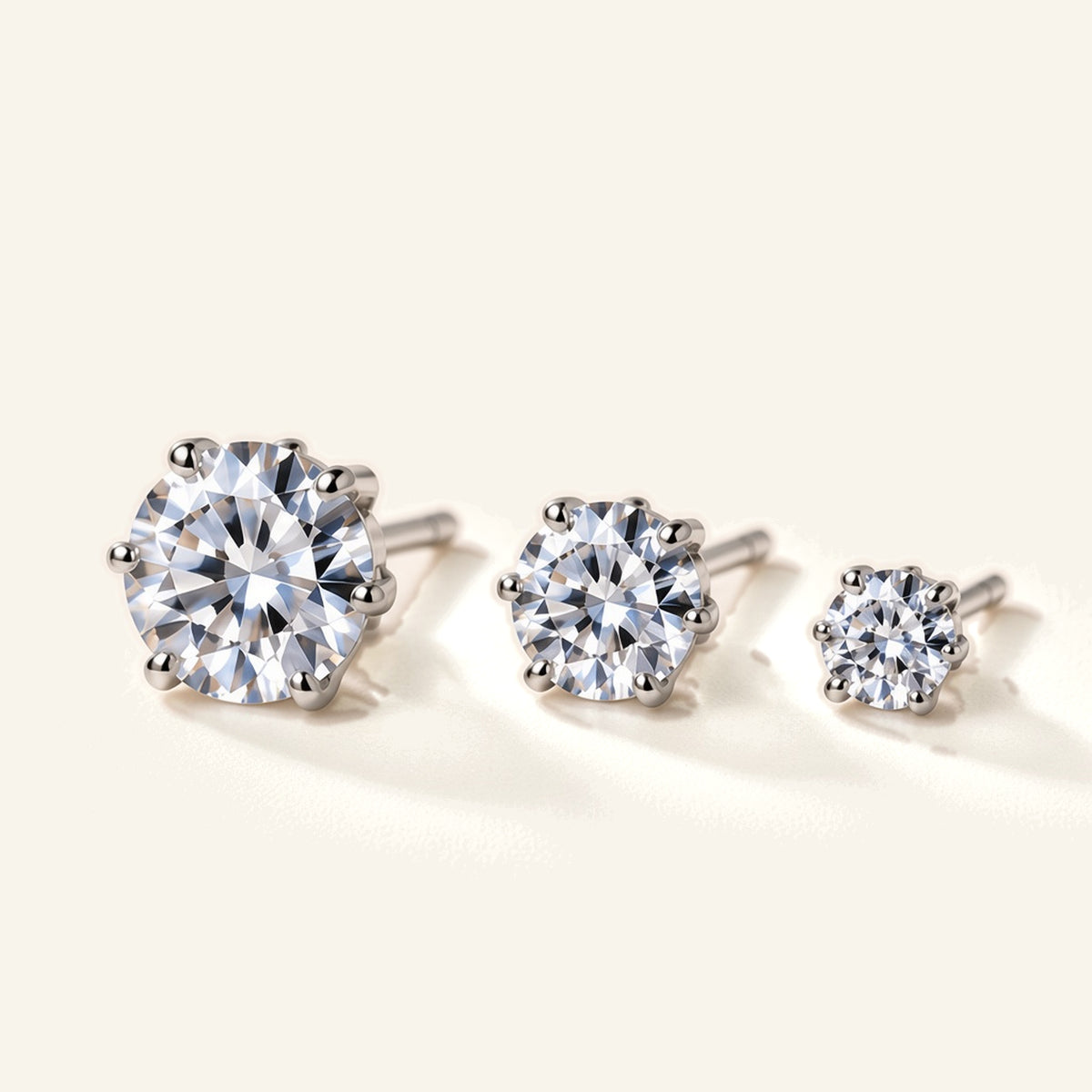 Denoon London solitaire crystal stud earrings, set of three in silver-tone, flat lay on cream