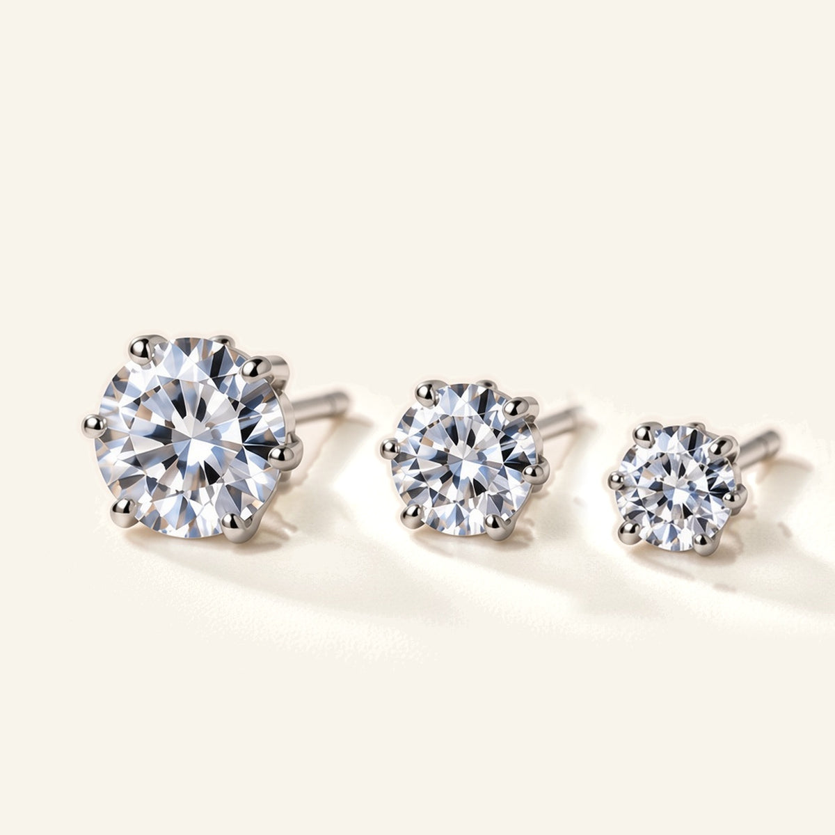 Denoon London Solitaire Crystal Stud Earrings Set of 3 in silver-tone, 6mm, 5mm and 4mm, flat lay on cream