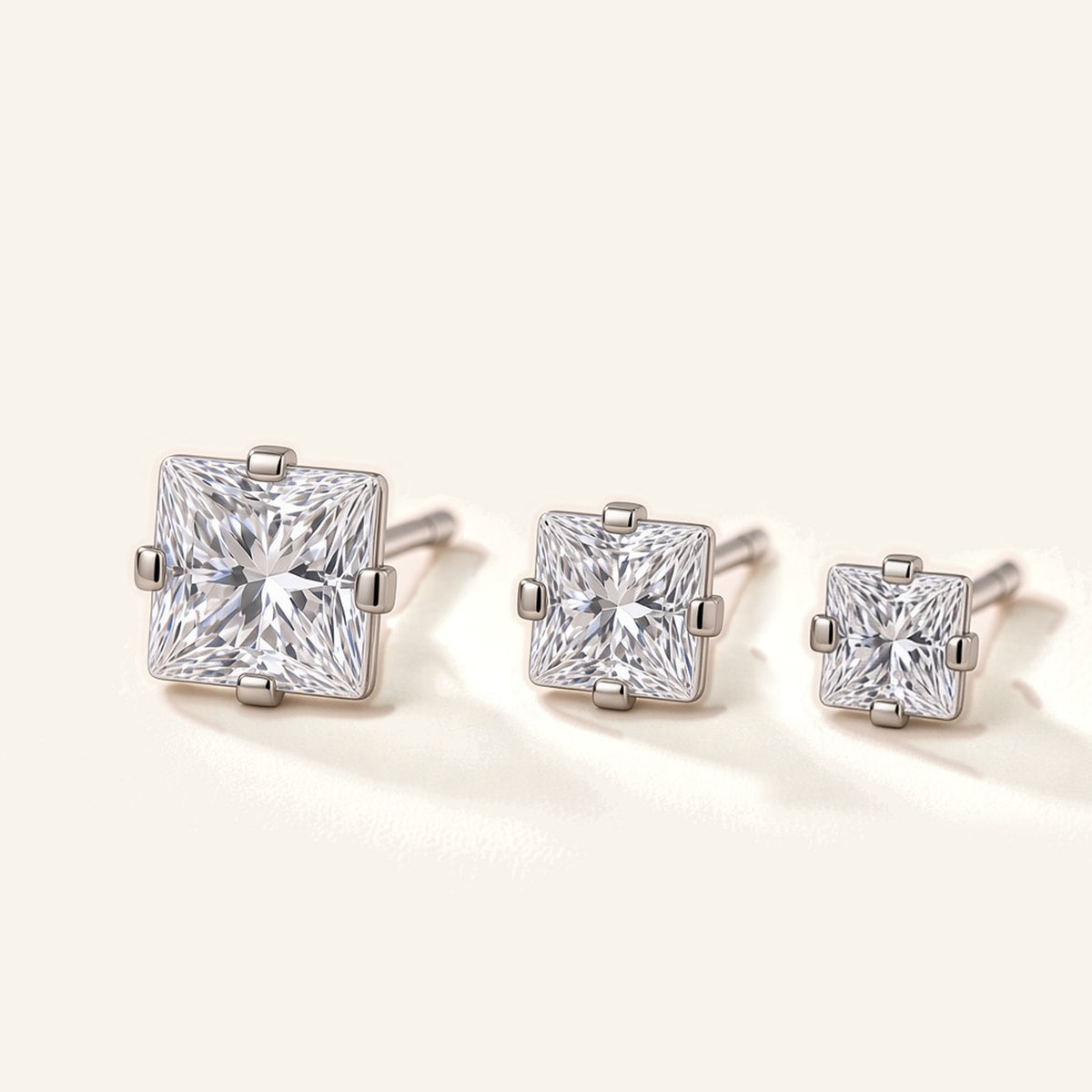 Denoon London Square Crystal Stud Earrings Set of 3 in silver-tone, 6mm, 5mm and 4mm, flat lay on cream